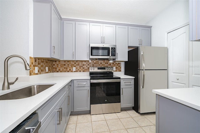 kitchen featuring appliances with stainless steel finishes, backsplash, gray cabinetry, sink, and light tile patterned floors