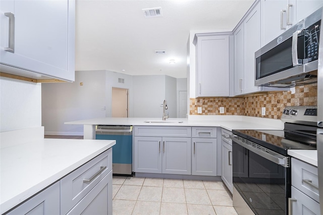 kitchen featuring gray cabinetry, sink, stainless steel appliances, tasteful backsplash, and light tile patterned floors