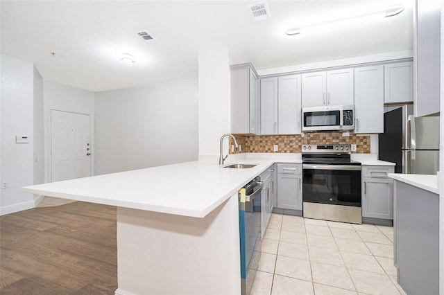 kitchen featuring tasteful backsplash, gray cabinets, sink, and stainless steel appliances