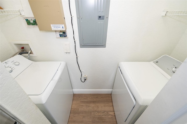 laundry room featuring electric panel, washer and clothes dryer, and hardwood / wood-style floors