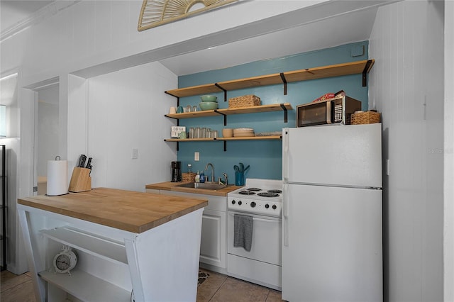 kitchen with sink, wood counters, white appliances, wooden walls, and light tile patterned floors