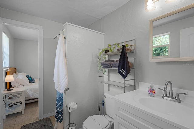 bathroom with tile patterned floors, vanity, toilet, and a wealth of natural light