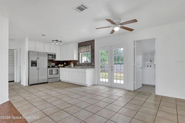 kitchen with appliances with stainless steel finishes, french doors, ceiling fan, white cabinets, and light tile patterned flooring