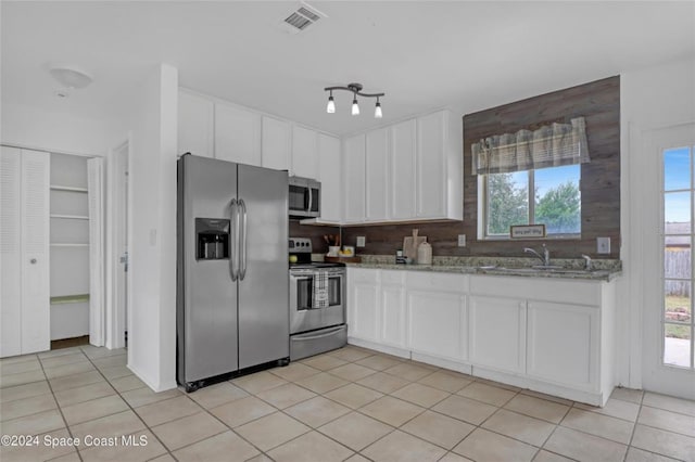 kitchen featuring light stone countertops, appliances with stainless steel finishes, backsplash, sink, and white cabinets