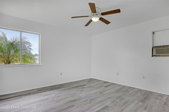 spare room with ceiling fan, cooling unit, and light wood-type flooring