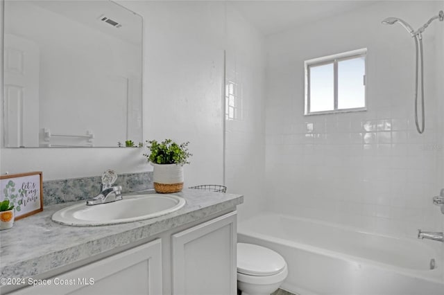 full bathroom featuring vanity, tiled shower / bath combo, and toilet