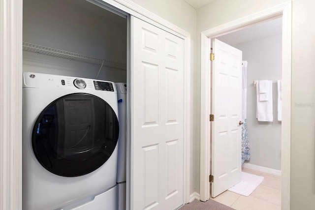 clothes washing area featuring washer / dryer and light tile patterned flooring