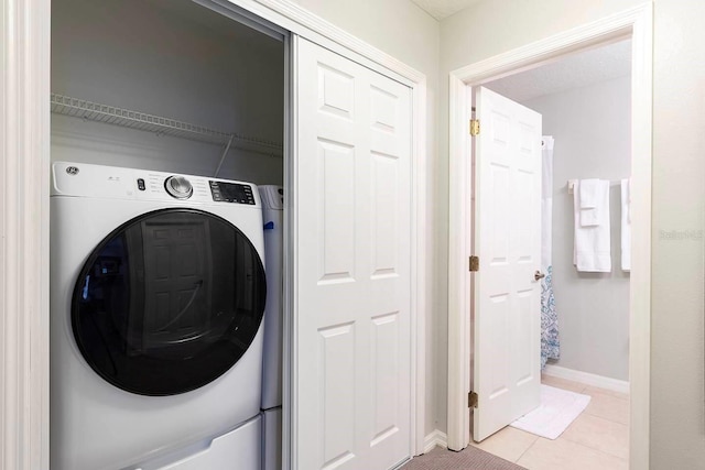 875 Assembly Ct, Reunion, FL 34747 - laundry area with washer / dryer, light tile patterned flooring, and baseboards