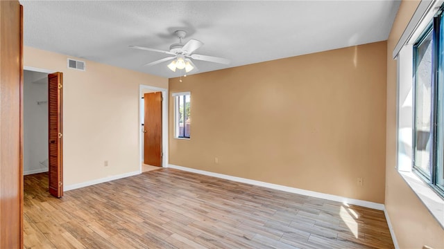 empty room with a textured ceiling, light hardwood / wood-style flooring, and ceiling fan