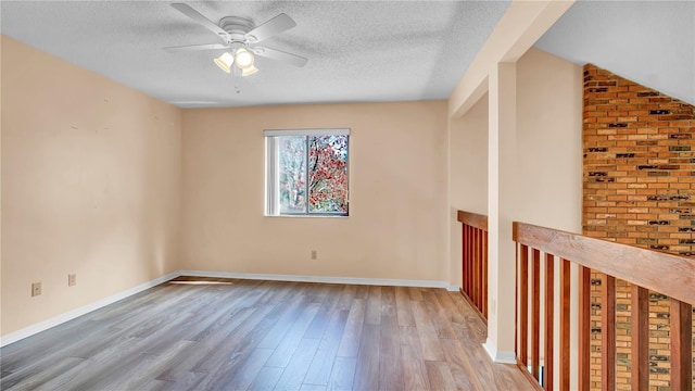 unfurnished room featuring ceiling fan, light hardwood / wood-style floors, and a textured ceiling