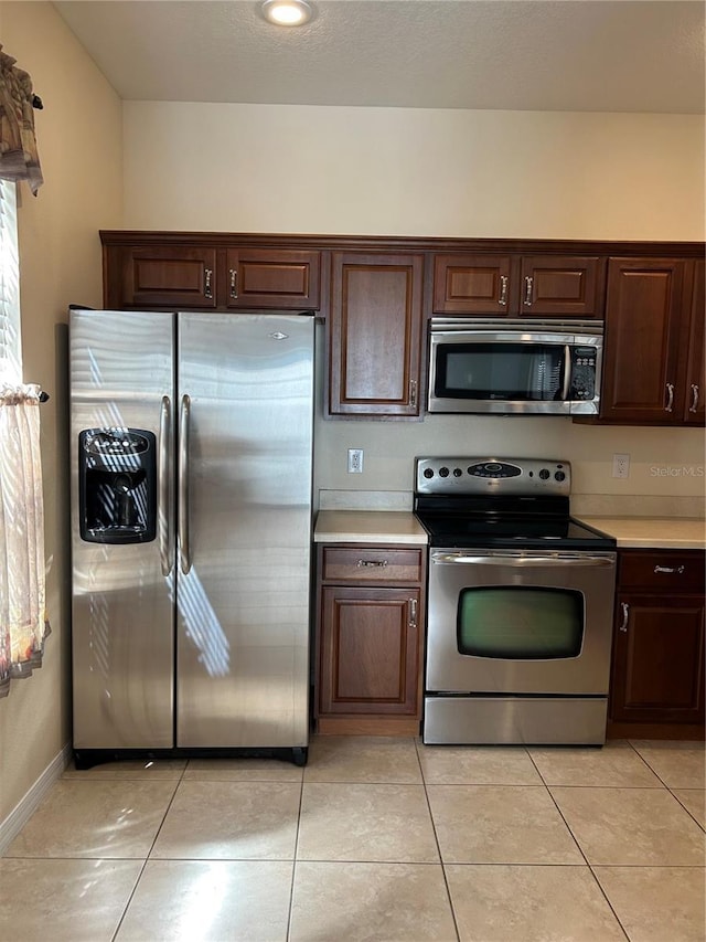 3031 San Jacinto Cir Unit 3031, Sanford, FL 32771 - kitchen featuring appliances with stainless steel finishes, light countertops, dark brown cabinets, light tile patterned floors, and baseboards