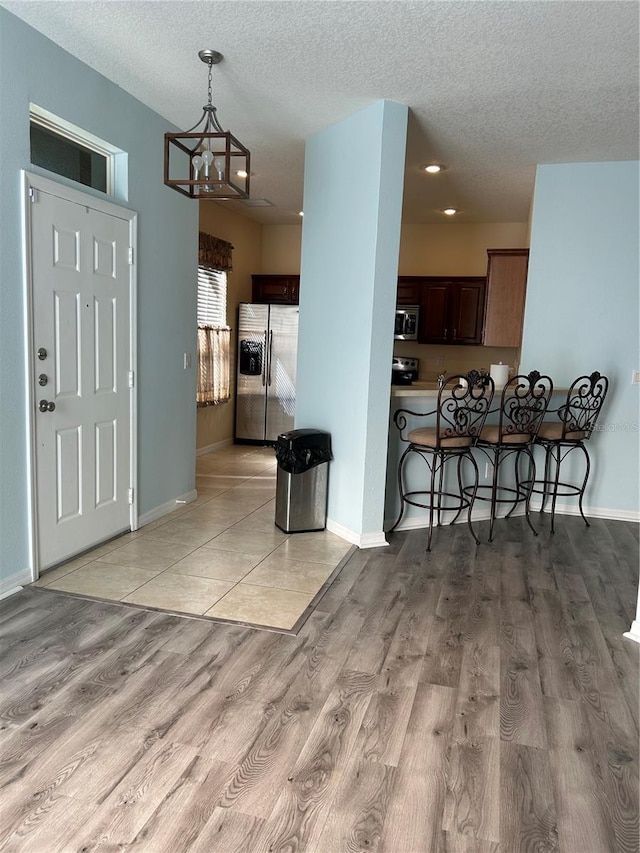 3031 San Jacinto Cir Unit 3031, Sanford, FL 32771 - kitchen featuring appliances with stainless steel finishes, a kitchen bar, a textured ceiling, light wood-style flooring, and baseboards