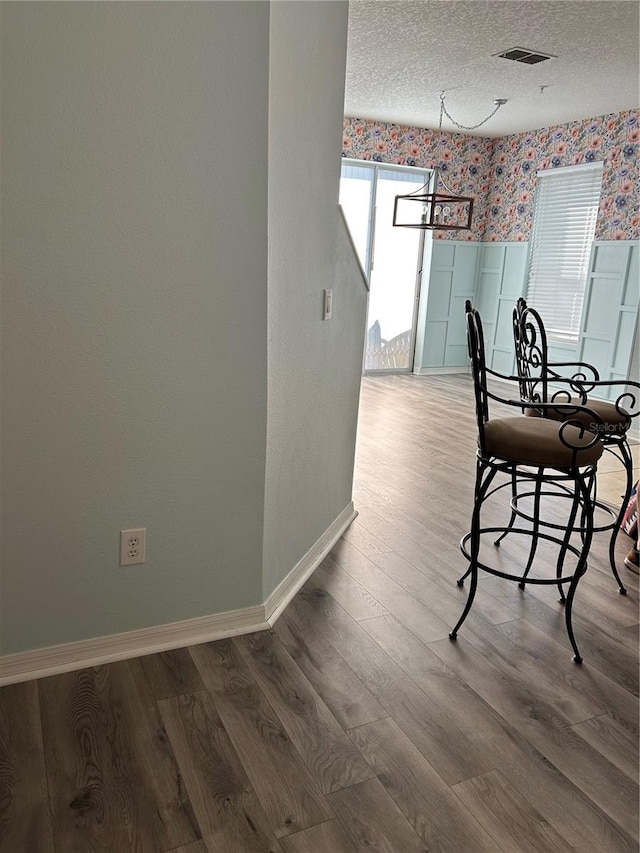 unfurnished dining area with wood-type flooring and a textured ceiling