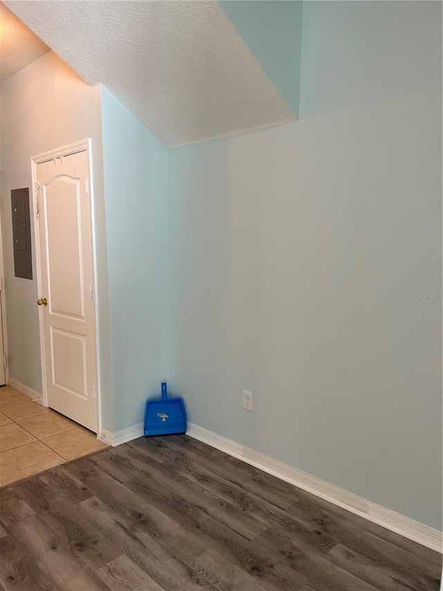 empty room featuring wood-type flooring, a textured ceiling, and electric panel