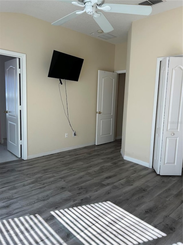 unfurnished bedroom with dark hardwood / wood-style flooring, a closet, and ceiling fan