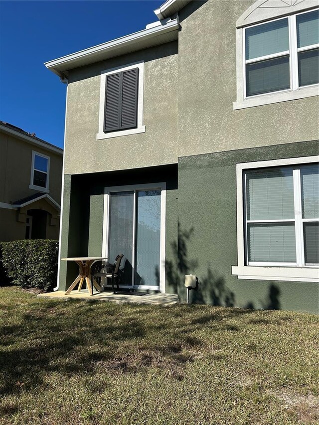 back of property featuring a patio area and a lawn