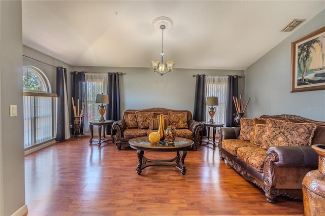 living room with a notable chandelier, wood-type flooring, and vaulted ceiling