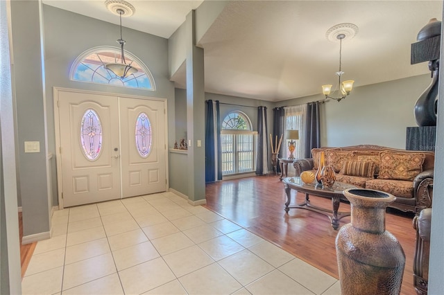 foyer with light wood-type flooring, plenty of natural light, and a notable chandelier