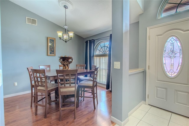 dining area with a chandelier, vaulted ceiling, and light hardwood / wood-style flooring