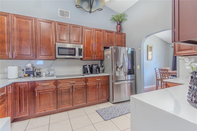 kitchen with light tile patterned floors, stainless steel appliances, and high vaulted ceiling