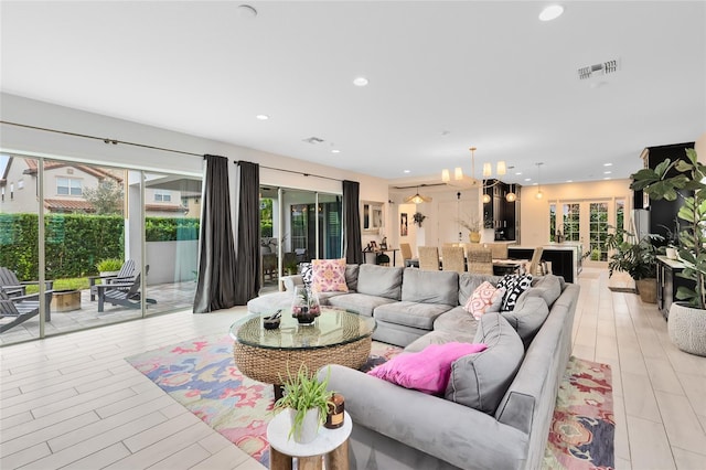 living room featuring light wood-type flooring, an inviting chandelier, and a wealth of natural light