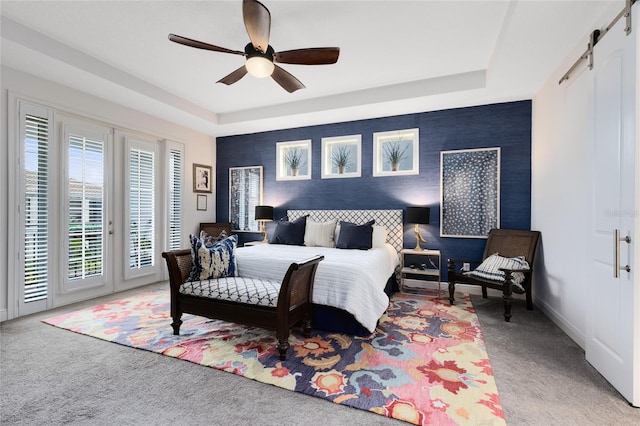 carpeted bedroom featuring access to outside, a barn door, ceiling fan, and a raised ceiling