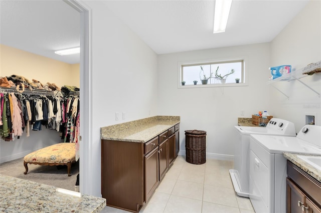 laundry room featuring washer and clothes dryer, light tile patterned floors, and cabinets