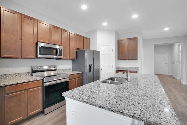 kitchen with light stone counters, light hardwood / wood-style floors, sink, and stainless steel appliances