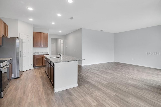 kitchen featuring appliances with stainless steel finishes, sink, light hardwood / wood-style flooring, and an island with sink