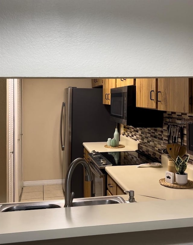 kitchen with light tile patterned floors, stainless steel appliances, tasteful backsplash, and sink