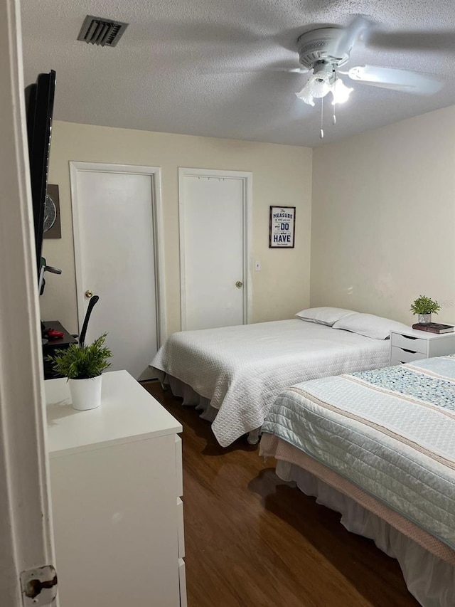 bedroom featuring ceiling fan, dark hardwood / wood-style flooring, and a textured ceiling