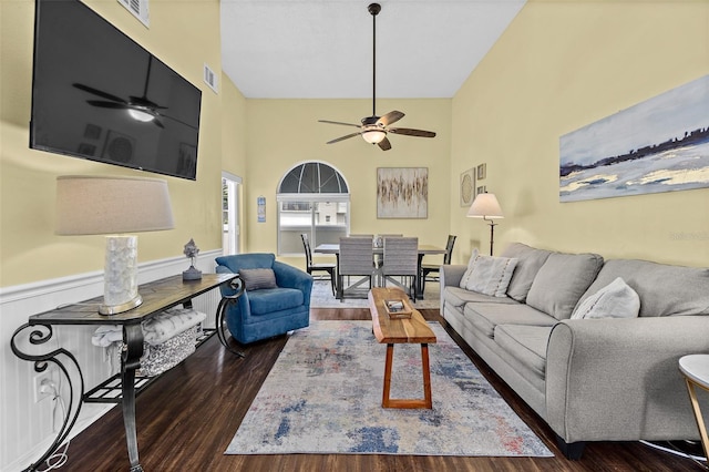 living room featuring a high ceiling, ceiling fan, and dark wood-type flooring