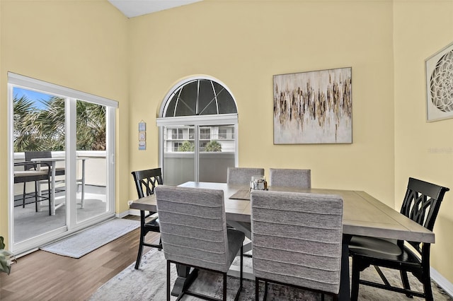 dining space with hardwood / wood-style flooring and a high ceiling