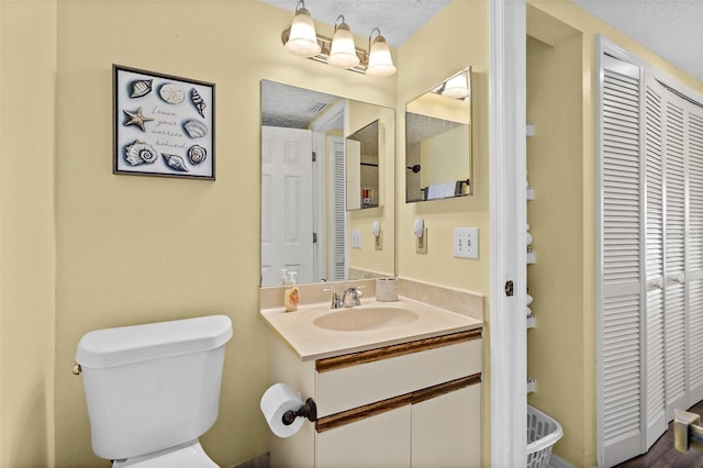 bathroom featuring hardwood / wood-style floors, vanity, toilet, and a textured ceiling