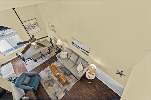 unfurnished living room with wood-type flooring, ceiling fan, and a high ceiling