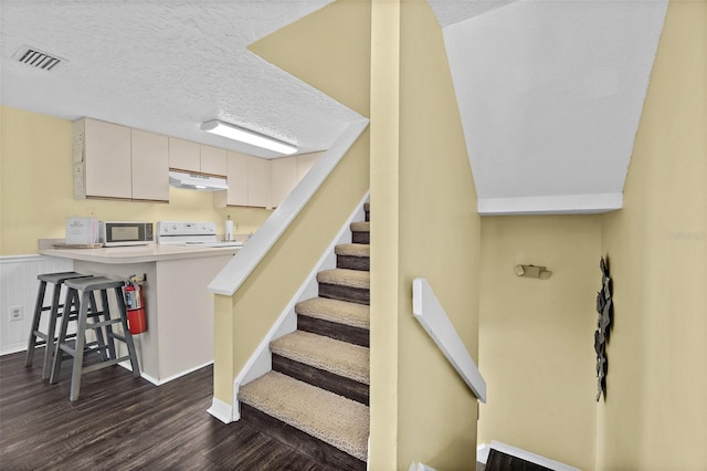 stairs with hardwood / wood-style floors and a textured ceiling