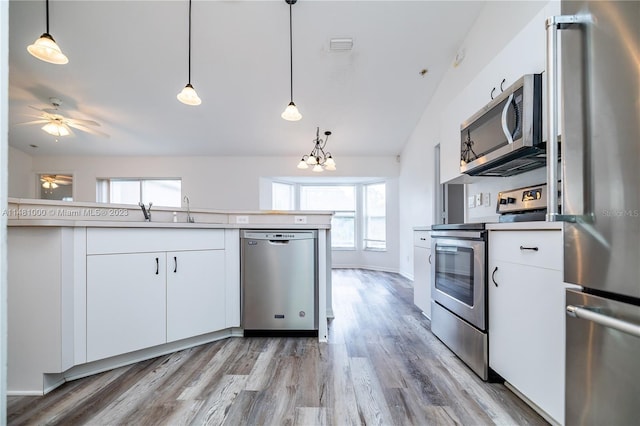 kitchen with light hardwood / wood-style flooring, white cabinets, decorative light fixtures, and appliances with stainless steel finishes