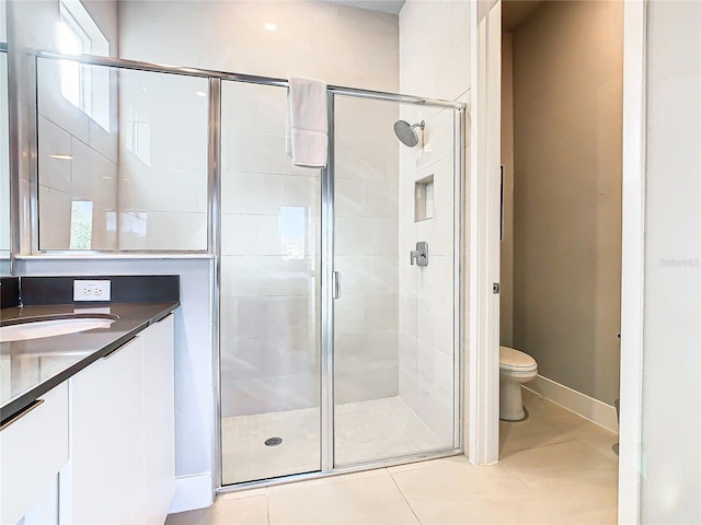 bathroom with tile patterned floors, vanity, a shower with shower door, and toilet