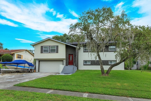 raised ranch with a front yard, stone siding, an attached garage, and concrete driveway