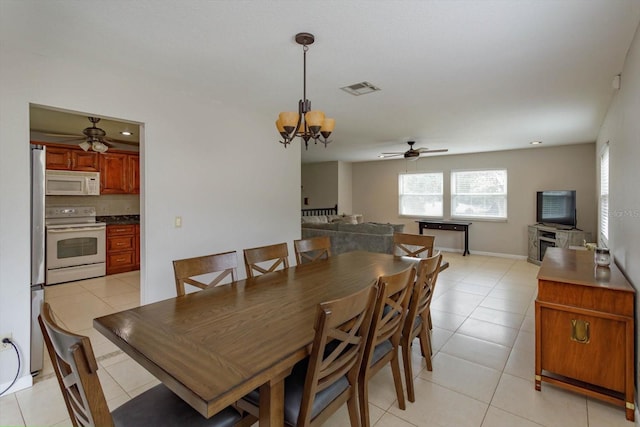 tiled dining space featuring ceiling fan with notable chandelier