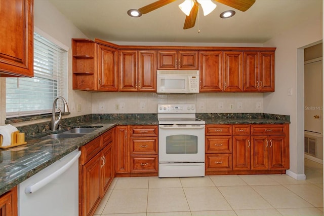 kitchen featuring dark stone counters, white appliances, ceiling fan, sink, and light tile patterned floors