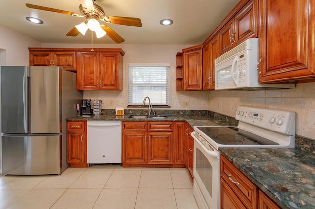 kitchen featuring ceiling fan, sink, dark stone counters, white appliances, and light tile patterned floors