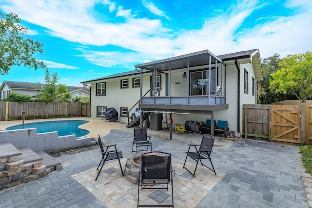 back of house featuring a sunroom, a patio area, a fenced in pool, and an outdoor fire pit