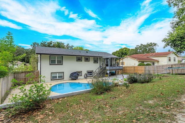 rear view of property with a sunroom, a fenced in pool, a yard, and a patio