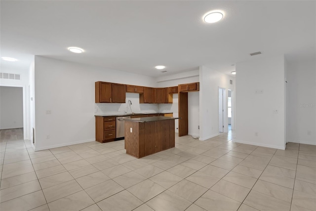 kitchen featuring dishwasher, a kitchen island, sink, and light tile patterned flooring