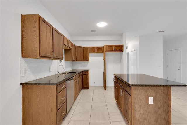 kitchen with dishwasher, sink, dark stone counters, decorative backsplash, and a center island