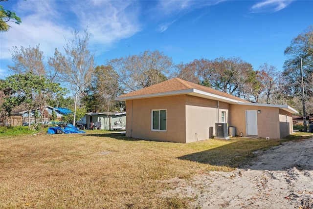 rear view of property with central AC unit and a yard