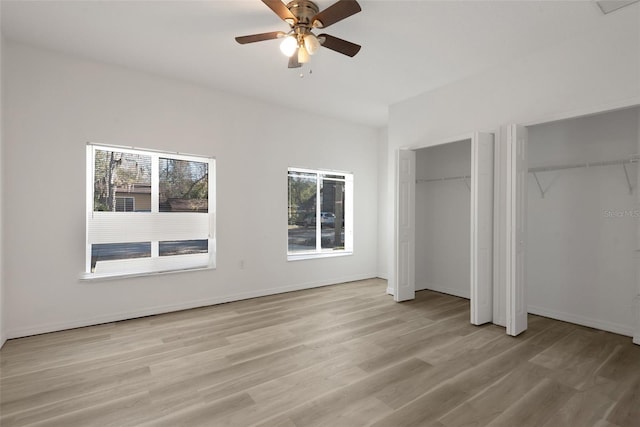 unfurnished bedroom with ceiling fan, light hardwood / wood-style flooring, and multiple closets