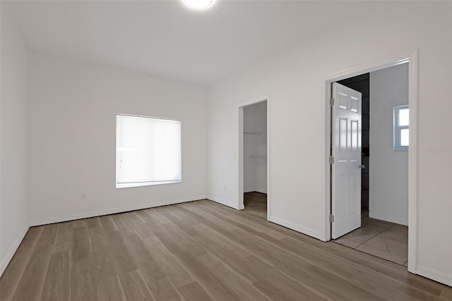 unfurnished bedroom with a closet, a spacious closet, and light hardwood / wood-style flooring