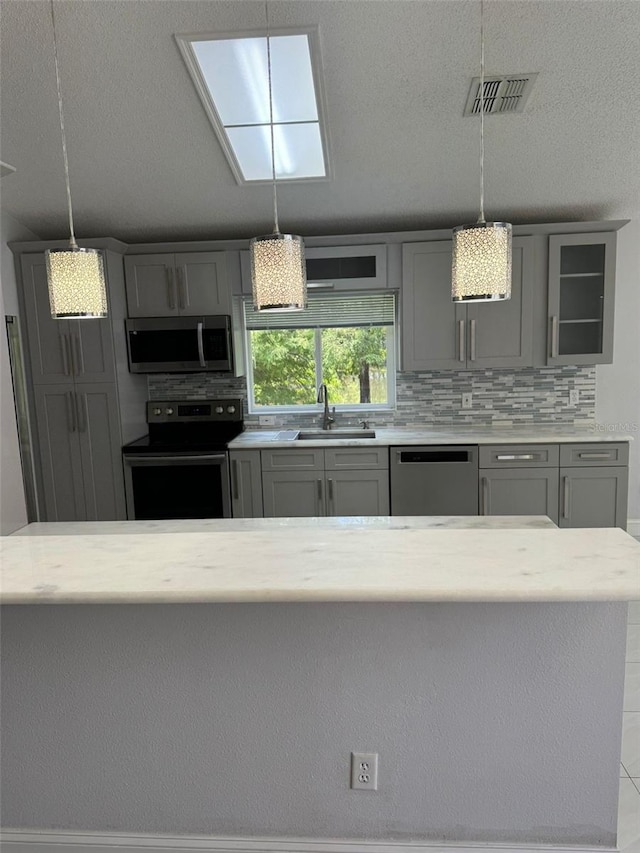 kitchen featuring tasteful backsplash, sink, pendant lighting, and appliances with stainless steel finishes